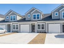 Charming townhome showcasing a gray exterior, garage, and well-maintained landscaping under a clear blue sky at 587 Harrison Mill St. # 587, Myrtle Beach, SC 29579