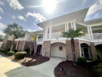 Inviting two-story condo featuring brick accents, covered balconies, and lush landscaping, perfect for relaxed coastal living at 700 Pickering Dr. # 103, Murrells Inlet, SC 29576