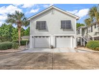 Two-story beach home with a two-car garage, complemented by tropical palm trees and a light gray exterior at 1125 Camellia Dr., Surfside Beach, SC 29575