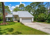 Charming single-story home featuring a metal roof, attached garage, and well-manicured lawn at 144 Springfield Rd., Pawleys Island, SC 29585