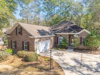 Charming single-Gathering home featuring brick exterior, attached garage, and well-manicured landscaping, creating inviting curb appeal at 1668 Club Circle, Pawleys Island, SC 29585