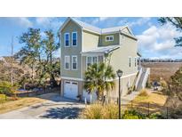 Charming three-story home with a two car garage, lush landscaping, and stunning waterfront views at 3 Half Shell Ct., Pawleys Island, SC 29585