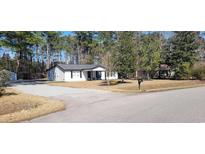 Charming white home with black trim and shutters, surrounded by trees and a well-maintained front yard at 4350 Monroe Circle, Myrtle Beach, SC 29588