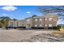 Attractive brick apartment building featuring well-maintained landscaping and an ample parking lot on a bright, sunny day at 500 Willow Greens Dr. # 500-G, Conway, SC 29526