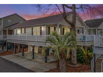 Charming elevated home with inviting front porch and covered parking, set against a colorful sunset sky at 6001 - 8008 S Kings Hwy., Myrtle Beach, SC 29575