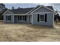 Charming one-story home with gray siding, black shutters, and a dark roof at 813 Highway 67, Loris, SC 29569