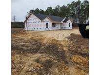 New construction featuring a dark roof and wrapped with protective white covering in a clearing surrounded by trees at 825 Highway 67, Loris, SC 29569
