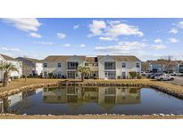 Condos reflect off a pond with a palm tree and blue skies above at 8830 Chandler Dr. # B, Surfside Beach, SC 29575