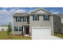 Charming two-story home with a well-maintained lawn, dark shutters, and a bright white garage door at 1004 Garden Sprout Dr, Galivants Ferry, SC 29544