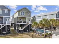 Charming elevated beach house with private pool, lush landscaping, and black wrought iron fence at 132 Garden City Retreat Dr., Murrells Inlet, SC 29576
