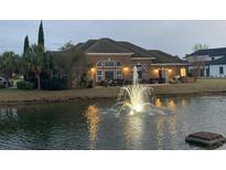 Brick home with a water fountain feature, chairs, and sliding glass doors overlooking the serene lake view at 1624 Portwest Dr., Myrtle Beach, SC 29579