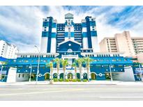Modern building exterior featuring blue and white accents, lush palm trees, and an inviting entrance at 2201 S Ocean Blvd. # 2010-2011, Myrtle Beach, SC 29577