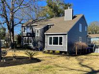 Charming two-story home with gray siding, a chimney, green lawn and well-kept landscaping at 316 13Th Ave. N, Surfside Beach, SC 29575