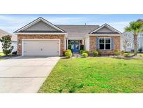 Charming single story home featuring a stone facade, attached garage, blue door, and meticulously maintained lawn at 455 Hyacinth Loop, Murrells Inlet, SC 29576