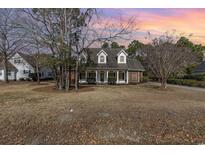 Charming two-story brick and white home with a welcoming front porch and mature landscaping at dusk at 4721 National Dr., Myrtle Beach, SC 29579