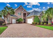 Stately brick home with a brick driveway, lush landscaping and a two-car garage at 707 Compass Pointe Dr, North Myrtle Beach, SC 29582
