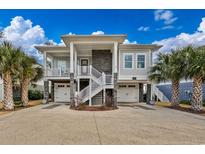 Beautiful elevated home with stone accents, dual garages, inviting stairs, and lush palm trees in the front yard at 1004 Marsh View Dr., North Myrtle Beach, SC 29582