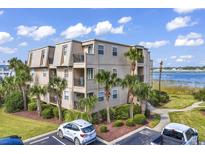 Exterior view of building with palm trees, green lawn and partial parking area under a blue cloudy sky at 1582 S Waccamaw Dr. # 44, Murrells Inlet, SC 29576