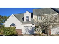 Charming townhome with a one-car garage and a mix of brick and white siding, enhanced by a beautiful flowering tree at 182 Wimbledon Way # 182, Murrells Inlet, SC 29576