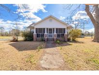 Charming single story home featuring a screened porch and landscaped front yard on a sunny day at 5092 Harrelson Ave., Loris, SC 29569
