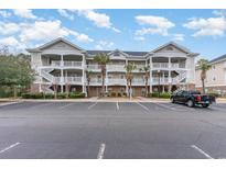 Three-story condo building with white balconies, a parking lot and some landscaping at 5801 Oyster Catcher Dr. # 724, North Myrtle Beach, SC 29582
