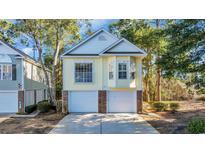 Charming two-story home with a two-car garage and light yellow siding surrounded by mature trees at 670 2Nd Ave. N, North Myrtle Beach, SC 29582