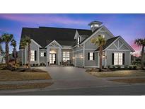 Charming two-story home with a well-manicured lawn, palm trees, and a welcoming entrance at twilight at 6892 Belancino Blvd., Myrtle Beach, SC 29572