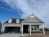 New construction gray home with covered porch and attached two-car garage showcases modern design and curb appeal at 1257 Crested Iris Way, North Myrtle Beach, SC 29582