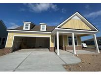 Charming single-story home with yellow siding, dormer windows, and an attached two-car garage at 1257 Crested Iris Way, North Myrtle Beach, SC 29582