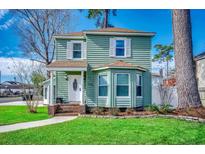 Charming two-story home with green siding, white shutters, a landscaped yard, and beautiful curb appeal at 1551 Victoria Ln., Myrtle Beach, SC 29577