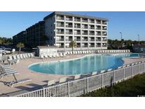 Inviting outdoor pool area with lounge chairs and views of the condo building and beautifully manicured landscaping at 5905 S Kings Highway # 416-A, Myrtle Beach, SC 29575