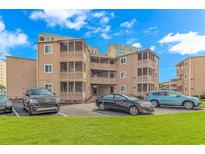 A charming tan condo building with parking and green space at 609 Hillside Dr. S. # E-18, North Myrtle Beach, SC 29582