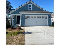 Charming blue home featuring a white garage door, black front door, and well-maintained lawn at 1241 Lady Bird Way, North Myrtle Beach, SC 29582