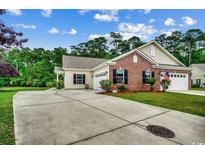 Charming home featuring a well-manicured lawn, brick accents, double garage, and long driveway at 196 Rose Water Loop, Myrtle Beach, SC 29588