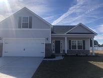 Charming two-story home with a two car garage, gray siding, and a well manicured lawn at 275 Stillbrook Dr., Longs, SC 29568