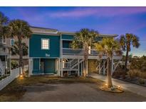 Inviting coastal home featuring a turquoise exterior, white railings, and lush palm trees in the landscaped front yard at 409 25Th Ave. N, North Myrtle Beach, SC 29582
