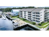 Waterfront condo building with private wooden pier, gazebo, and lounge chairs overlooking the river at 4445 Kingsport Rd. # 406, Little River, SC 29566