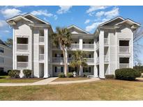 Beautiful white condo building featuring multiple stories and balconies with tropical landscaping at 597 Blue River Ct. # H2, Myrtle Beach, SC 29579
