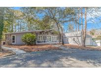 Inviting home featuring stone accents, a covered porch, and a well-maintained gravel driveway surrounded by mature trees at 67 Massick Ln., Pawleys Island, SC 29585