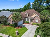 Charming brick home featuring a well-manicured lawn, mature trees, and a spacious driveway at 9134 Abingdon Dr., Myrtle Beach, SC 29579