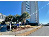 View of the South Hampton building with palm trees and manicured lawn against a blue sky at 9820 Queensway Blvd. # 303, Myrtle Beach, SC 29572