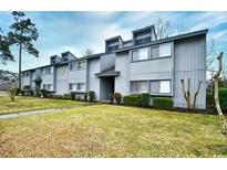 View of the two-story townhome with gray siding, trimmed shrubs and an expansive lawn at 10301 N Kings Hwy. # 15-8, Myrtle Beach, SC 29572