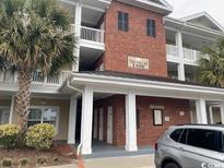 A sunny view of this condo building showcasing lovely architectural detail, palm trees and brick at 1101 Louise Costin Ln. # 1308, Murrells Inlet, SC 29576