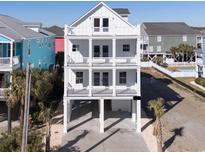 Three story white home with multiple balconies and outdoor living space at 1211-B N Waccamaw Dr., Garden City Beach, SC 29576