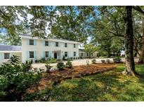 Two-story home with light brick, black roof and black door surrounded by green trees and landscaping at 201 River Rd., Georgetown, SC 29440