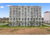 Large condo building featuring multiple floors, balconies, palm trees, and a well-maintained green space at 2151 Bridge View Ct. # 1-1103, North Myrtle Beach, SC 29582