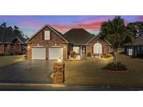 Charming brick home features a two-car garage, well-maintained lawn, and beautiful landscaping under a colorful sky at 387 Foxtail Dr., Longs, SC 29568