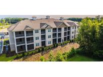 A modern, multi-story apartment building with screened-in porches, surrounded by trees at 395 S Crow Creek Dr. # 1704, Calabash, NC 28467