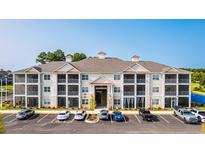 Apartment building featuring screened porches, light-colored siding, and ample parking at 395 S Crow Creek Dr. # 1710, Calabash, NC 28467