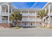 Attractive condo building featuring multiple levels, balconies, and lush palm tree landscaping in a beachfront community at 4803 Bovardia Pl. # 102, Myrtle Beach, SC 29577